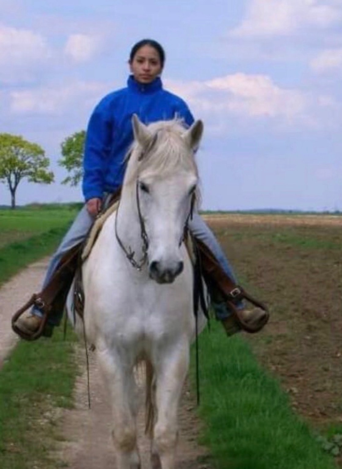 Nicola Gell riding a black horse along a path at Westbrook Horse Farm